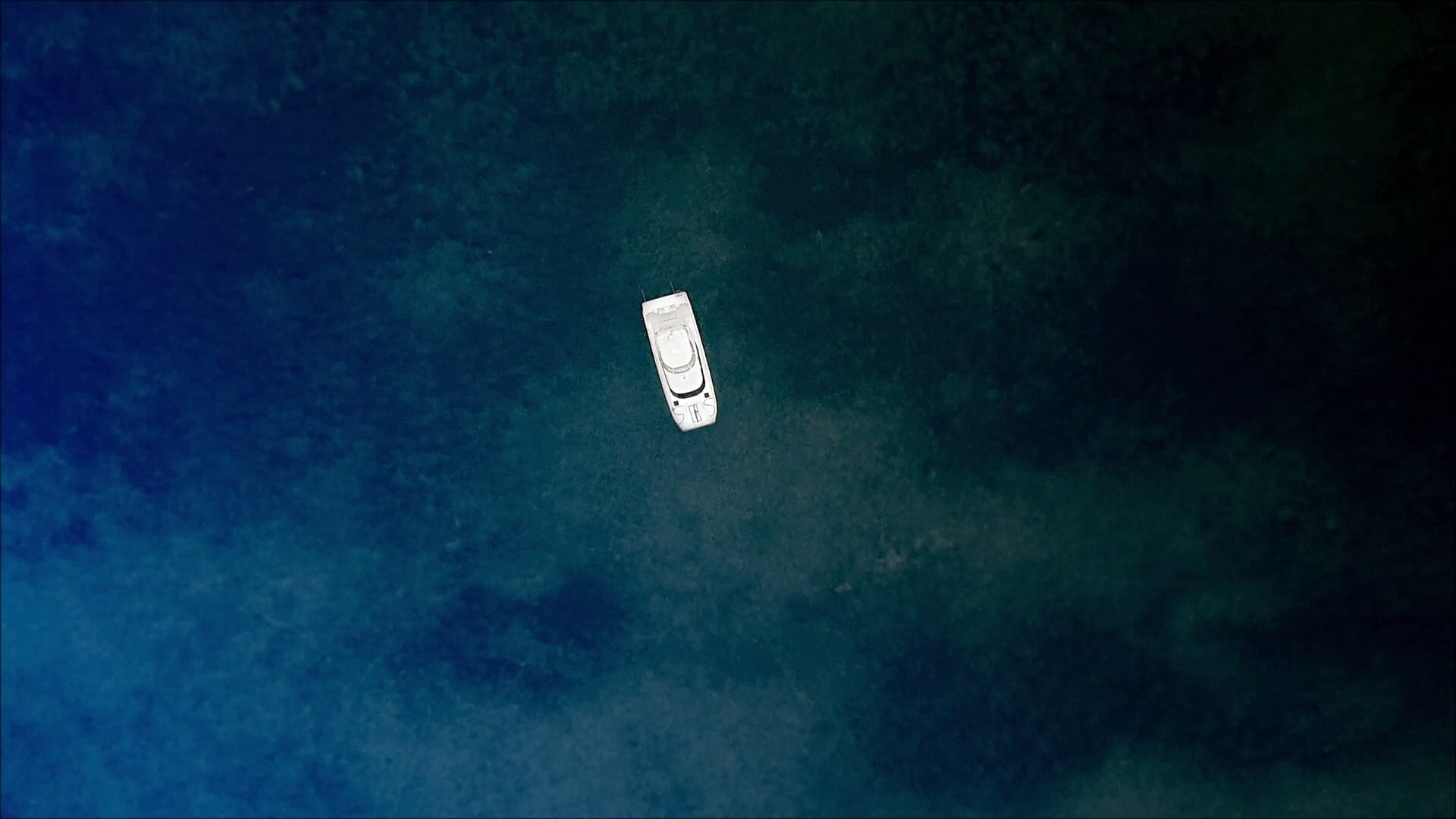 A screenshot from the film Harpoon. A white boat is stranded in the vast ocean with nothing around. 