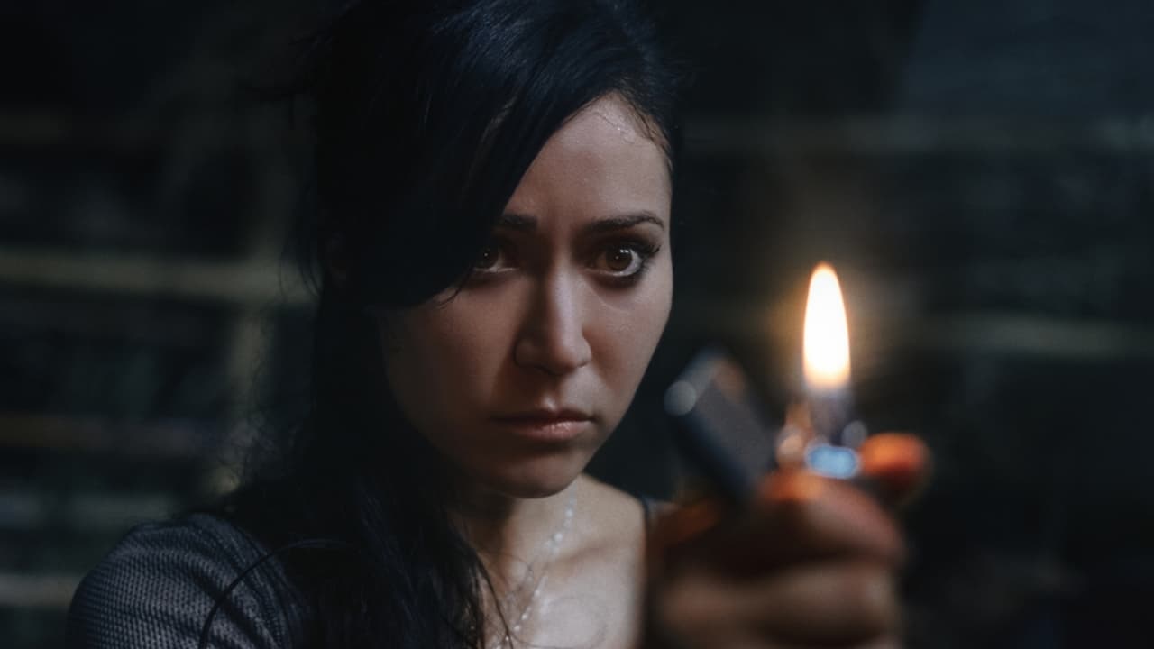 Screenshot from the film The Old Ways. A woman with dark hair holds up a lighter. 