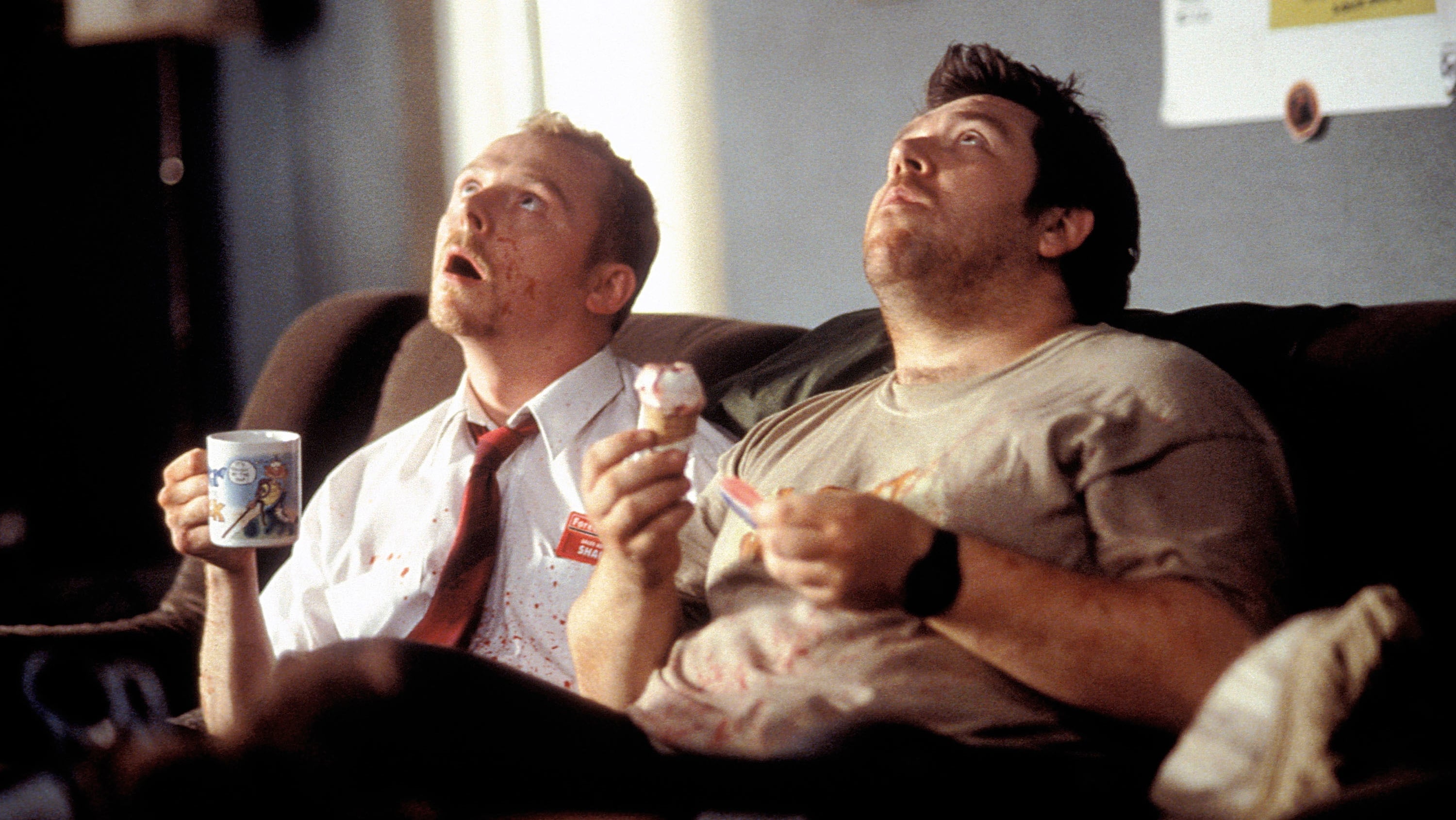 Screenshot from Shaun of the Dead. Two man with bloody clothes on look up at the ceiling with confused expressions on their face.