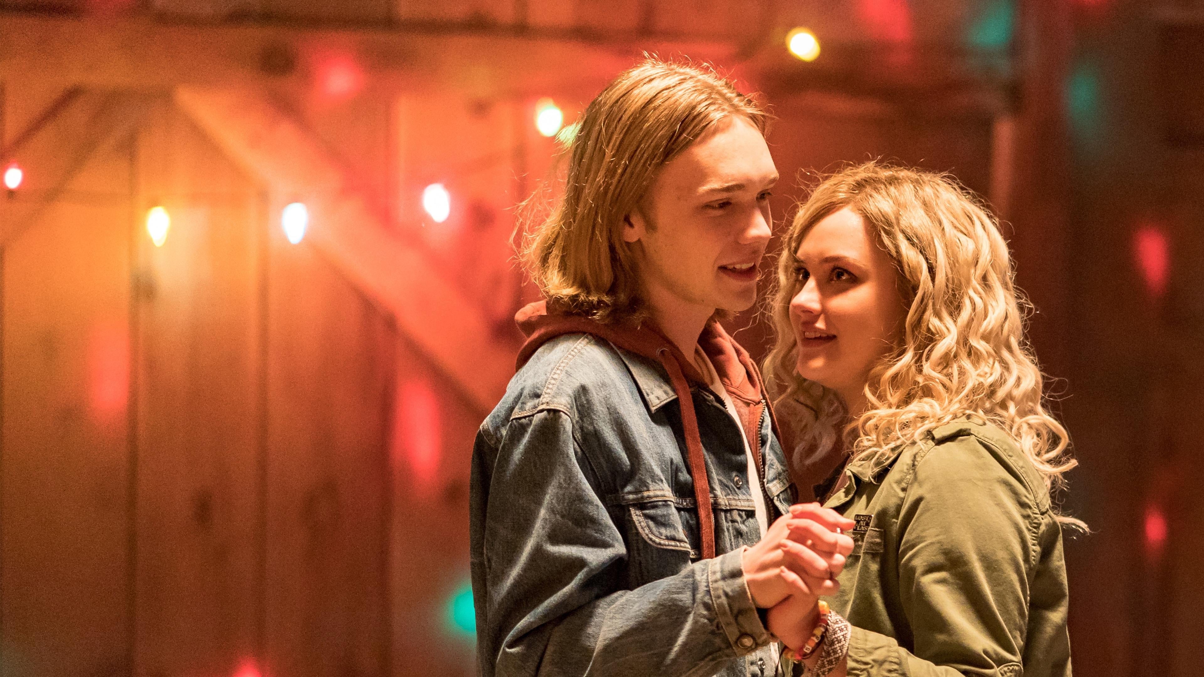 Screenshot from the film Spontaneous. Two young teens slow dance together with string lights in the background.